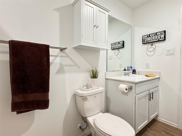 bathroom with toilet, baseboards, wood finished floors, and vanity