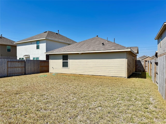 back of house with a yard and a fenced backyard