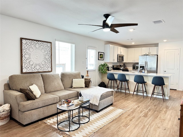 living room featuring light wood finished floors, visible vents, a ceiling fan, and recessed lighting