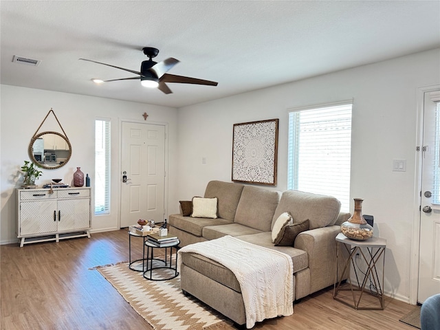 living area with baseboards, visible vents, ceiling fan, and wood finished floors