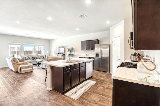 kitchen with visible vents, a sink, stainless steel appliances, light countertops, and dark brown cabinets