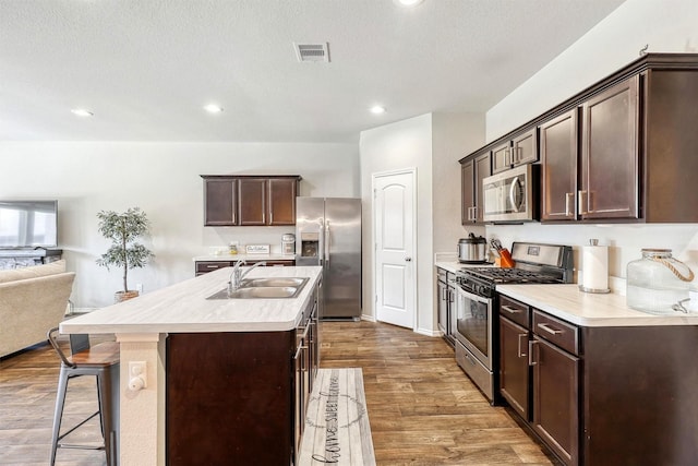 kitchen featuring a sink, dark brown cabinetry, dark wood-type flooring, and stainless steel appliances