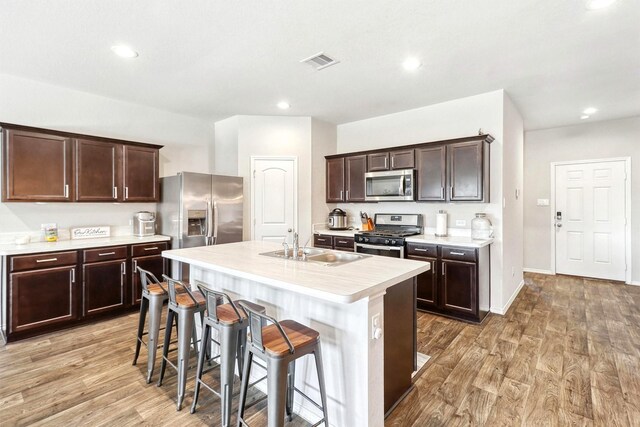 21023 Belmont Village Way, Katy, TX 77449 - kitchen with appliances with stainless steel finishes, light countertops, light wood finished floors, a breakfast bar area, and recessed lighting