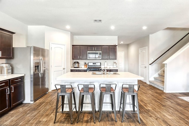 kitchen with visible vents, a kitchen breakfast bar, dark wood-style floors, stainless steel appliances, and a sink