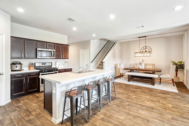 kitchen with light countertops, a kitchen breakfast bar, appliances with stainless steel finishes, light wood-style floors, and a sink