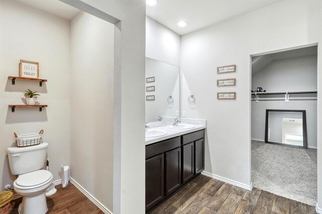 bathroom with toilet, wood finished floors, baseboards, and a sink