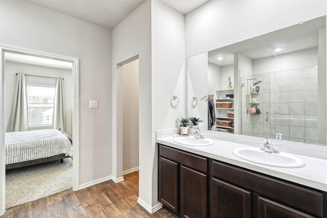 ensuite bathroom with double vanity, wood finished floors, ensuite bathroom, and a sink