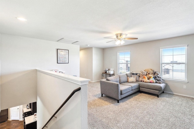 living area with a textured ceiling, attic access, baseboards, and dark colored carpet