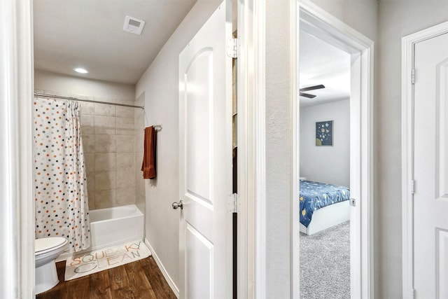 bathroom featuring visible vents, baseboards, toilet, shower / bath combo, and wood finished floors