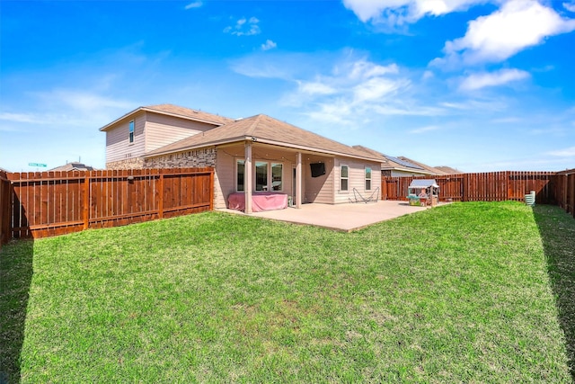 back of house with a fenced backyard, a lawn, and a patio