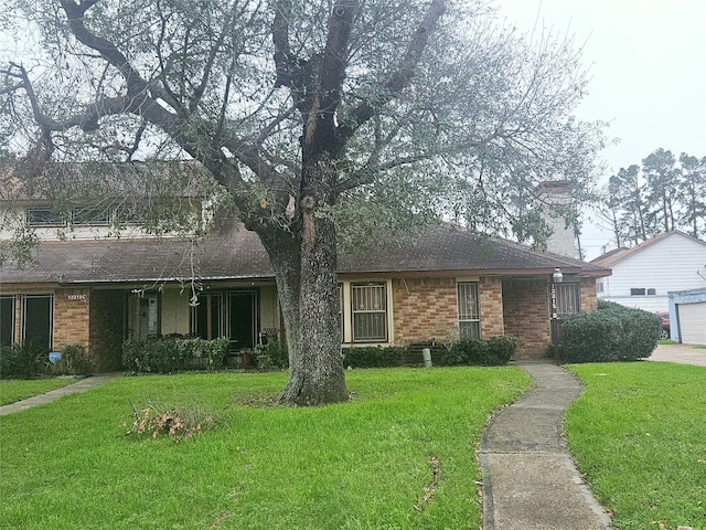 ranch-style house featuring roof with shingles, a front yard, and brick siding