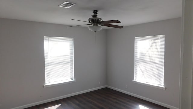 empty room featuring dark wood-style floors, baseboards, visible vents, and ceiling fan