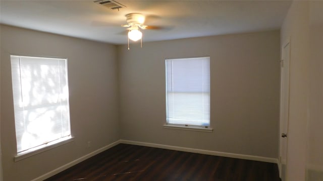 empty room with dark wood-type flooring, visible vents, and baseboards