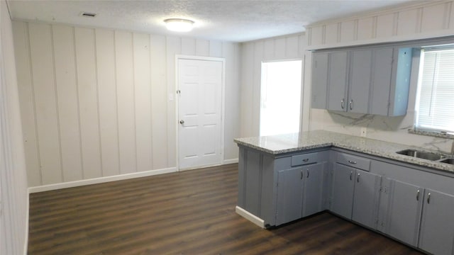 kitchen with dark wood finished floors, a sink, a peninsula, and gray cabinetry