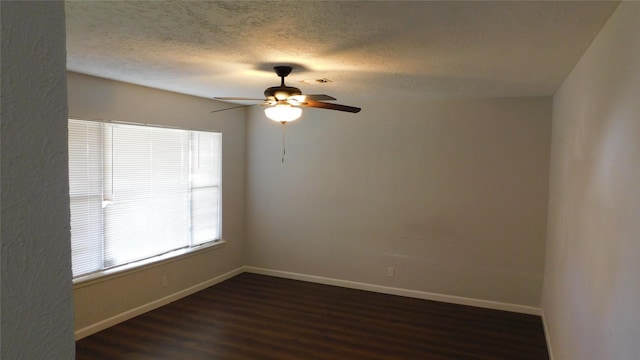 empty room featuring a textured ceiling, dark wood-type flooring, a ceiling fan, and baseboards