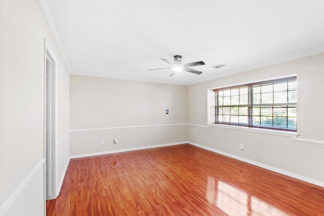 unfurnished room with a ceiling fan, visible vents, baseboards, and wood finished floors