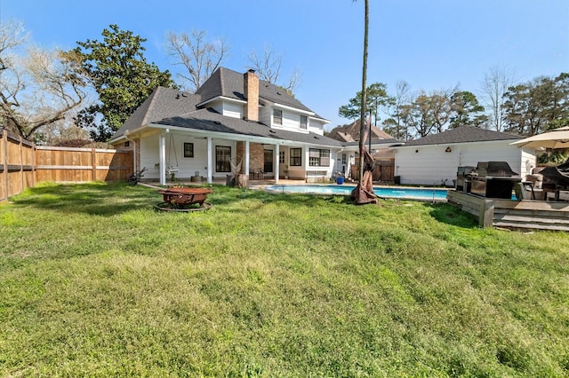 rear view of house featuring a fenced backyard, a fire pit, a fenced in pool, and a yard