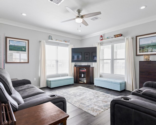 living room featuring ceiling fan, wood finished floors, visible vents, and crown molding