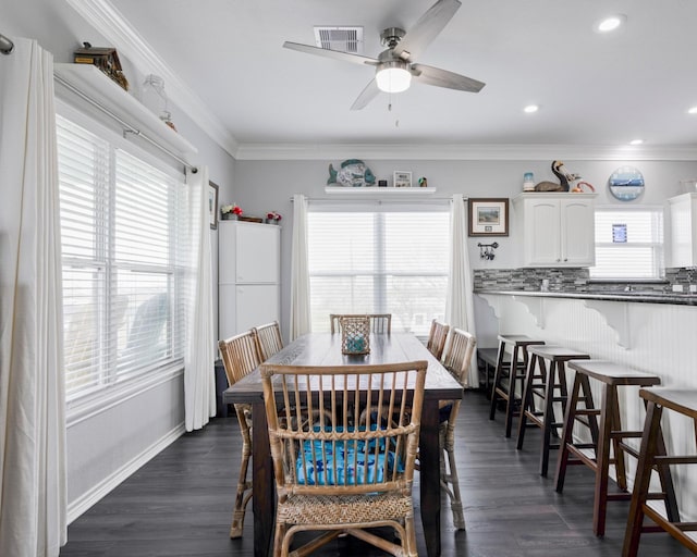 dining area featuring visible vents, dark wood-type flooring, a wealth of natural light, and ornamental molding