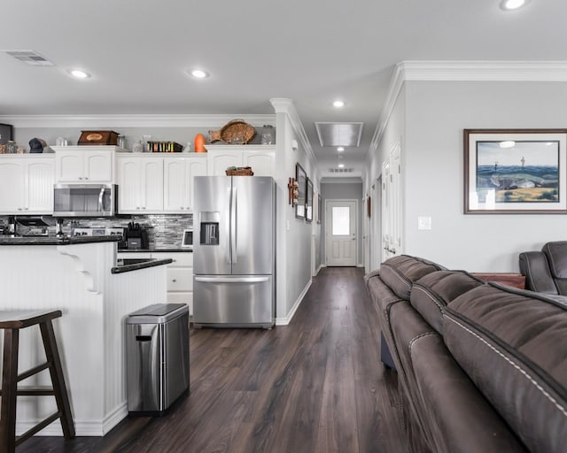 kitchen with open floor plan, appliances with stainless steel finishes, dark countertops, and a kitchen bar