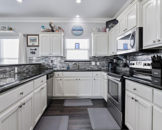 kitchen featuring stainless steel appliances, ornamental molding, a sink, and white cabinetry