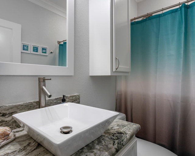 bathroom with toilet, crown molding, a sink, and a shower with shower curtain