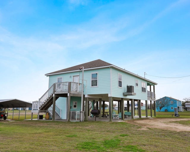 rear view of property with central air condition unit, stairs, a lawn, roof with shingles, and a carport