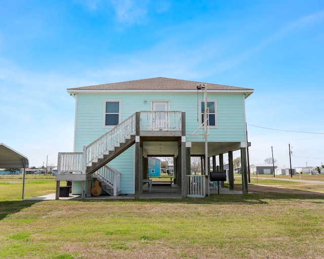 back of property with roof with shingles, a patio area, a yard, and stairs