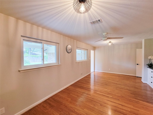 unfurnished living room with ceiling fan, light wood finished floors, visible vents, and baseboards