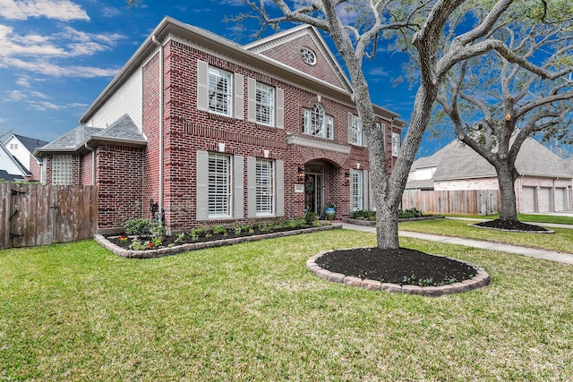 colonial-style house featuring a garage, a front yard, brick siding, and fence