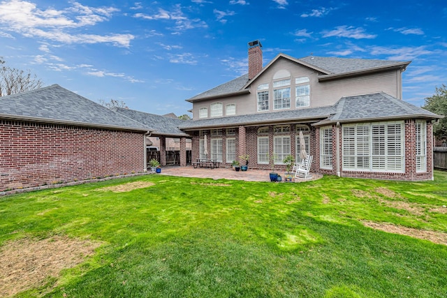 back of house with brick siding, a yard, and a chimney