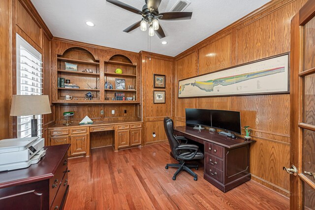 home office featuring a ceiling fan, built in study area, wood walls, and wood finished floors