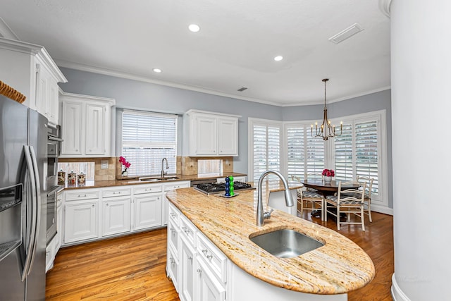 kitchen featuring white cabinets, a sink, and a center island with sink