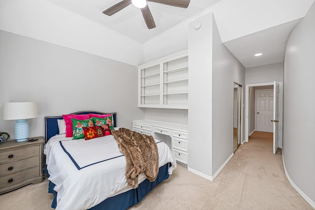 bedroom featuring light carpet, ceiling fan, built in study area, and baseboards