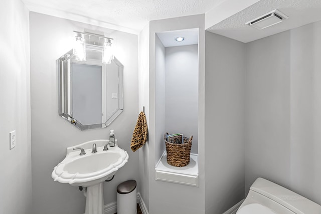 bathroom featuring a textured ceiling, toilet, and visible vents