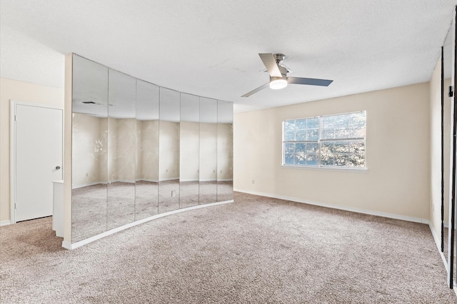 unfurnished bedroom with carpet floors, ceiling fan, a textured ceiling, and baseboards