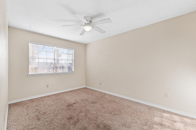 carpeted empty room with a ceiling fan, a textured ceiling, and baseboards