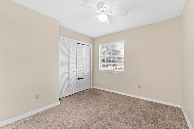 unfurnished bedroom with baseboards, ceiling fan, a textured ceiling, carpet floors, and a closet