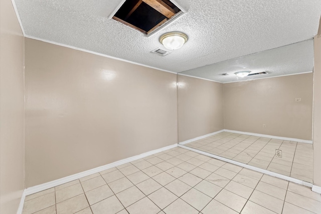 empty room featuring light tile patterned floors, baseboards, visible vents, ornamental molding, and a textured ceiling