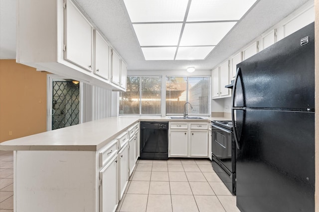 kitchen featuring light tile patterned floors, light countertops, a sink, a peninsula, and black appliances