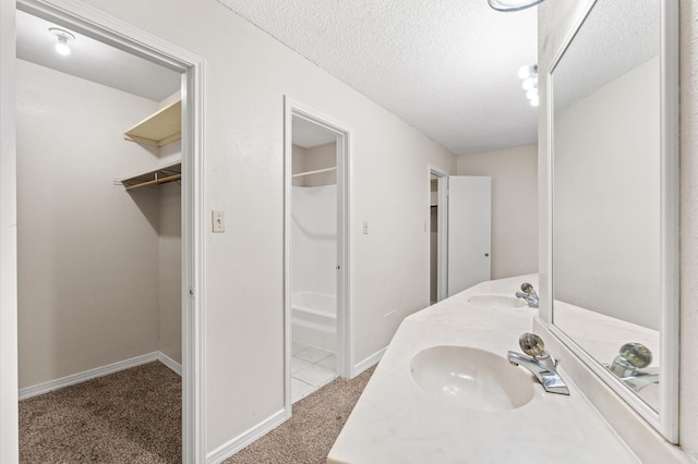 bathroom with a sink, a textured ceiling, baseboards, and double vanity