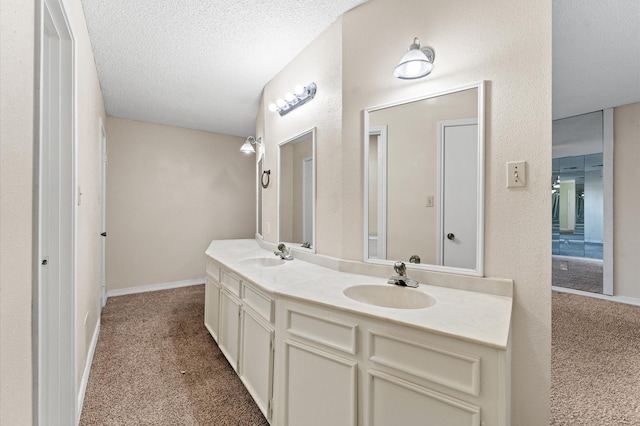 bathroom featuring double vanity, a textured ceiling, baseboards, and a sink