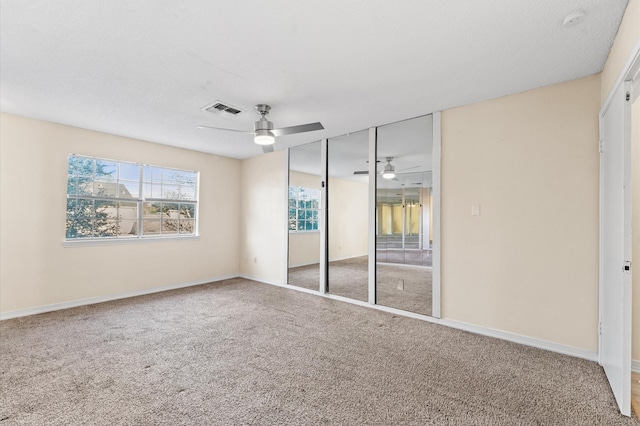 unfurnished bedroom featuring a closet, carpet flooring, visible vents, and a ceiling fan