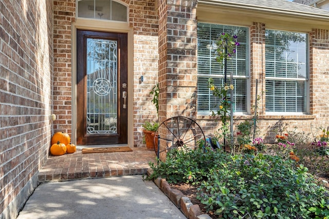 doorway to property with a shingled roof and brick siding