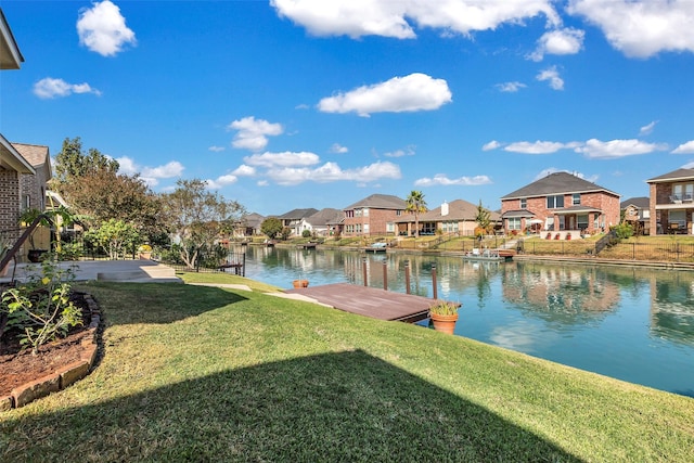 dock area with a water view, a residential view, a patio, and a yard