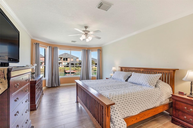 bedroom featuring visible vents, wood finished floors, and ornamental molding