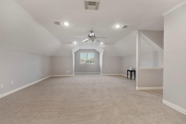 additional living space with visible vents, light carpet, vaulted ceiling, ceiling fan, and baseboards