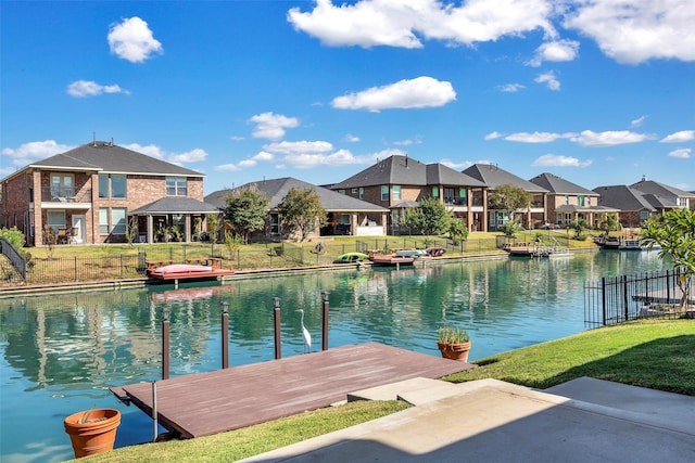 view of dock featuring a yard, a residential view, a water view, and fence