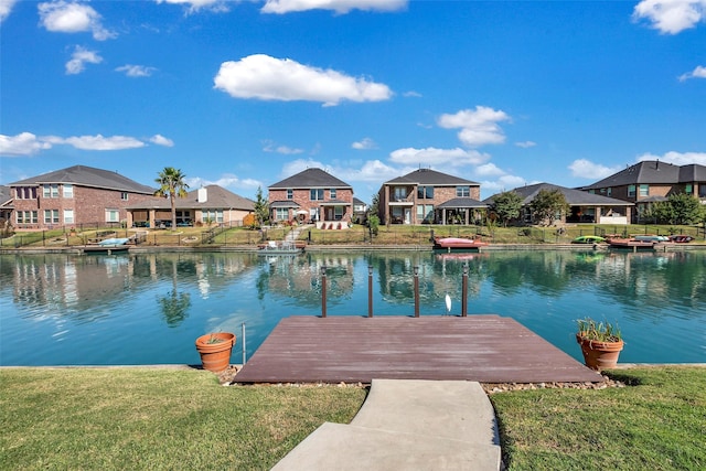 view of dock featuring a water view, a residential view, and a lawn