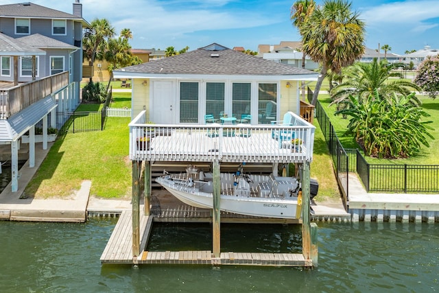 back of house with a shingled roof, a lawn, a deck with water view, and a fenced backyard